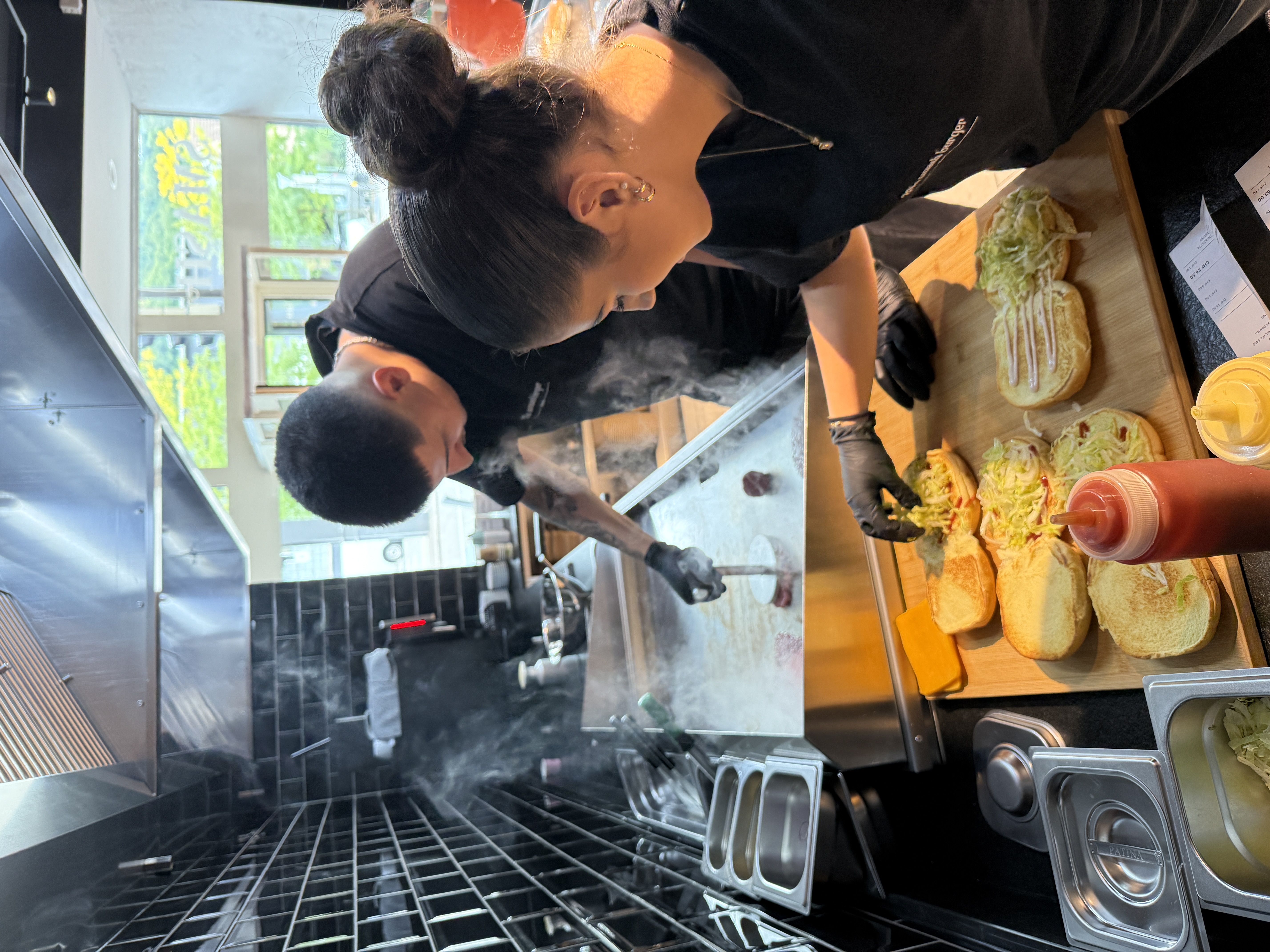 Team bereitet Smash Burger frisch auf der Grillplatte zu