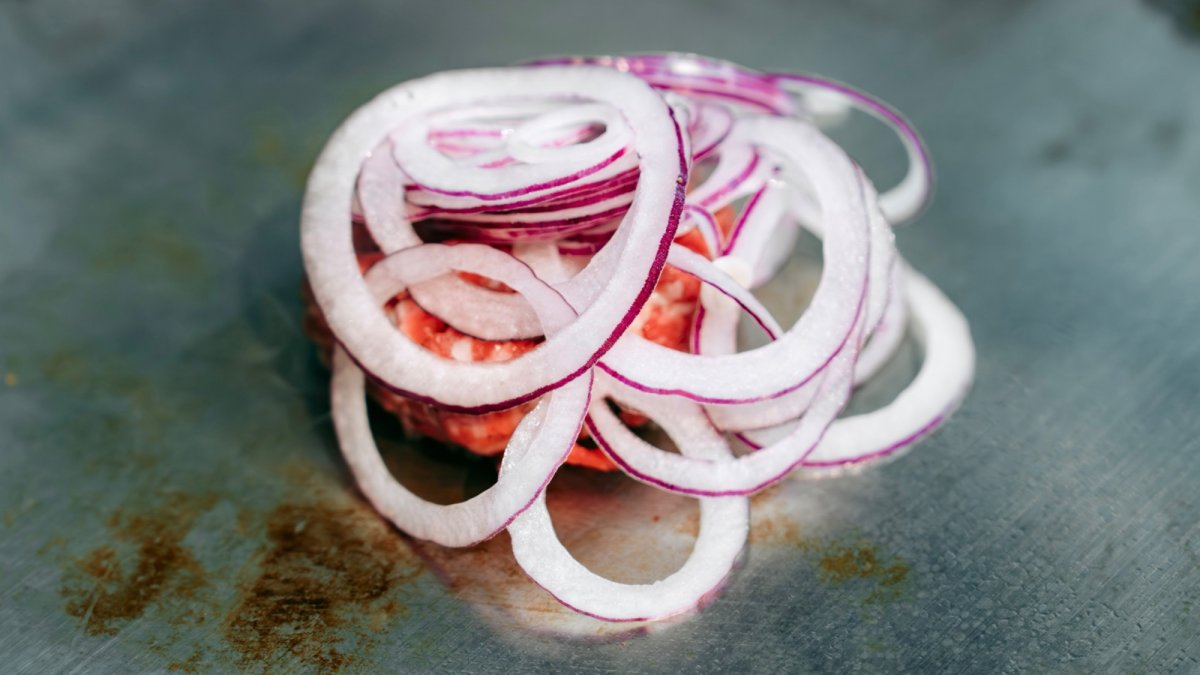 Frische rote Zwiebeln und Tomaten auf einem Smash Burger Patty